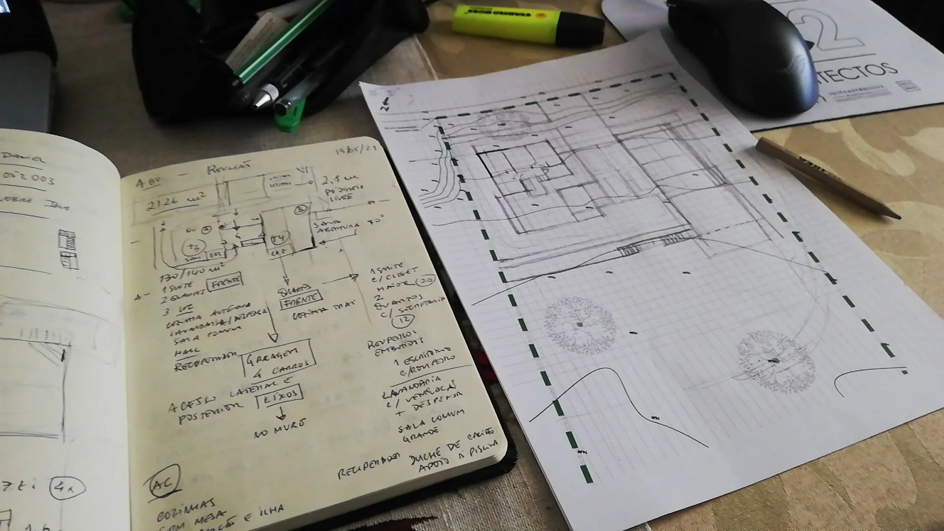 Caderno de esboços e desenhos de arquitectura sobre uma mesa de trabalho